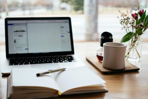 Photo of a laptop and a notebook on a desk